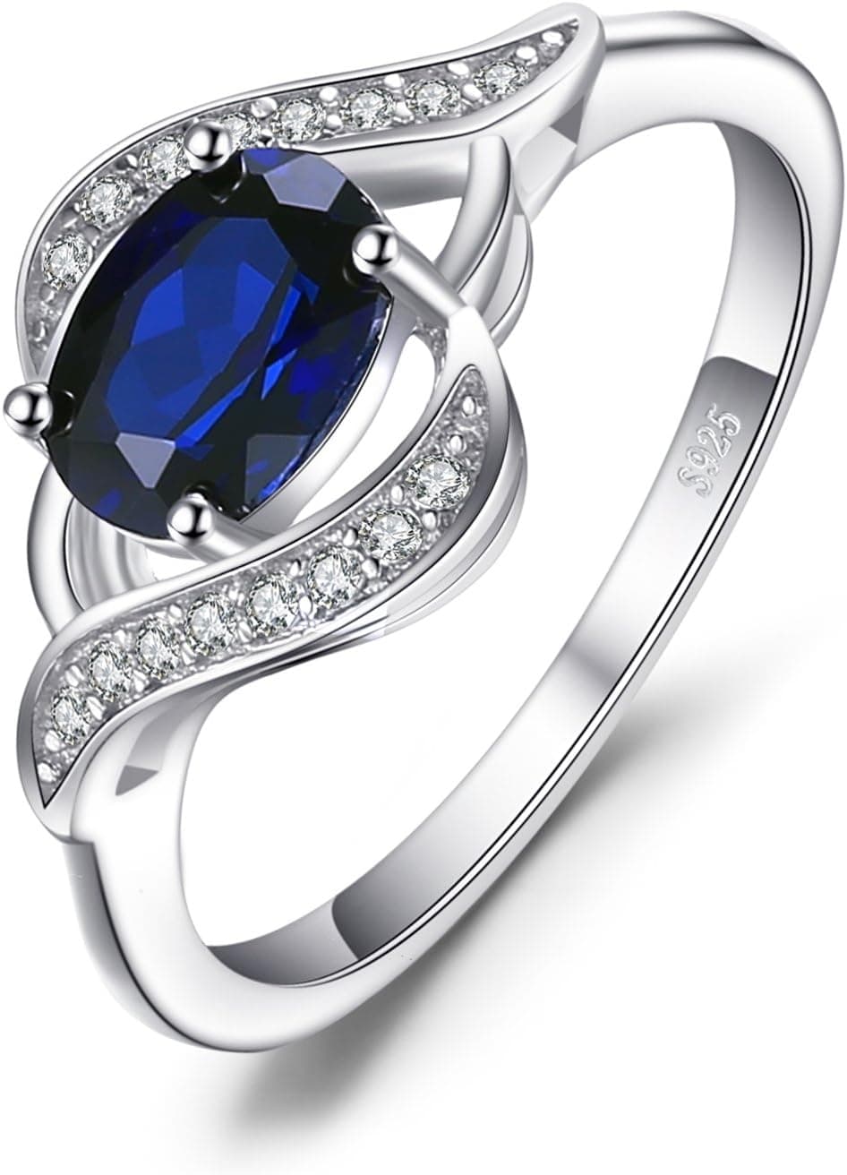 Anillo con banda ondulada de plata y zafiro azul ovalado rodeado de circonitas