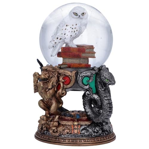 Bola de nieve de Hedwig posada sobre libros, con el león de Gryffindor y la serpiente de Slytherin flanqueando la base
