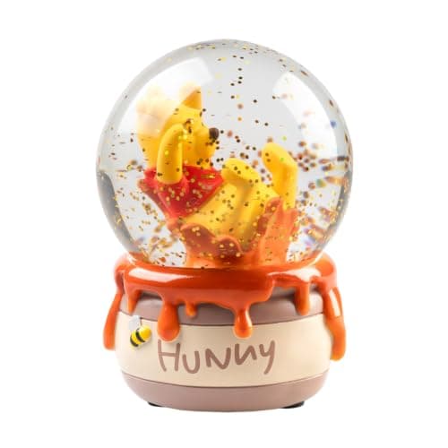Bola de nieve de Winnie the Pooh disfrutando de su tarro de miel, nieve dorada suspendida alrededor
