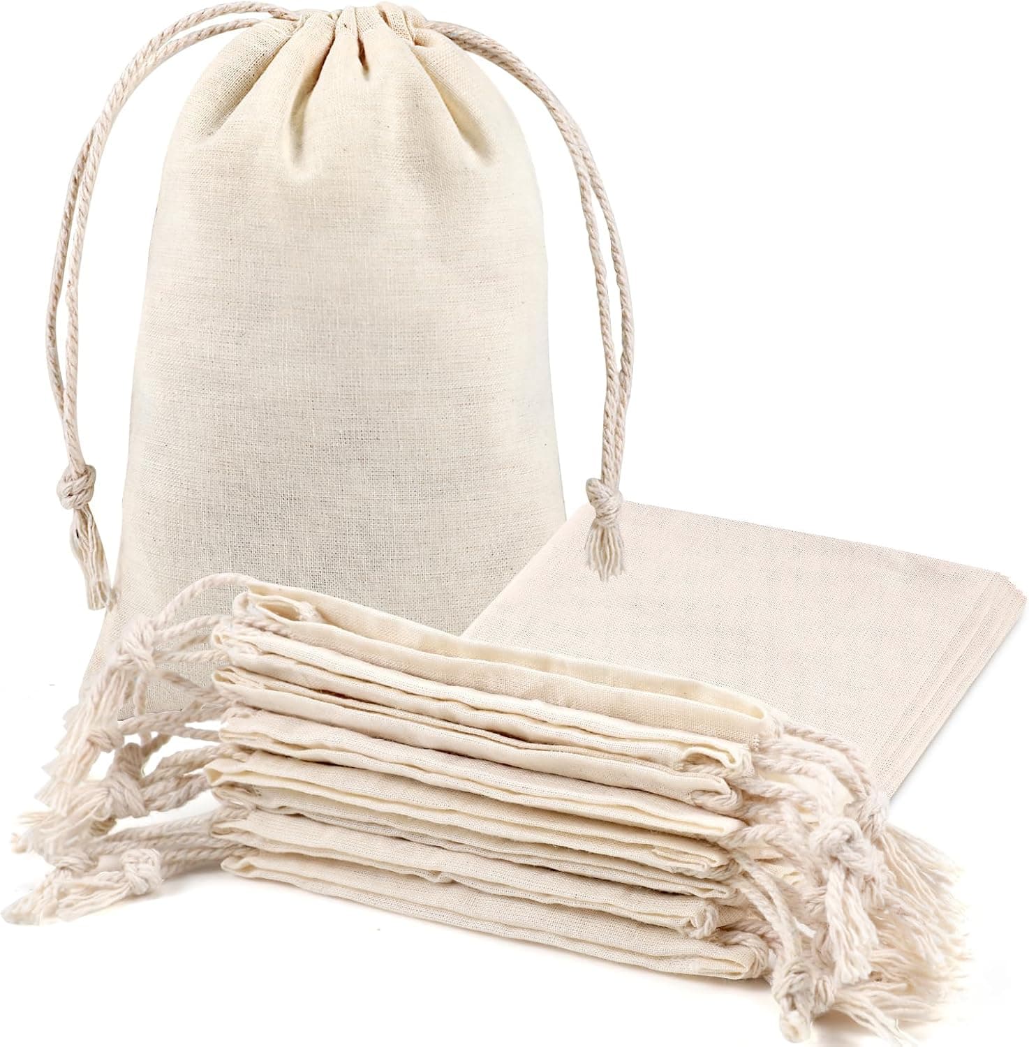 Varias bolsas de algodón crudo con cordón de cierre, colocadas sobre una superficie de fibra natural junto a una piña