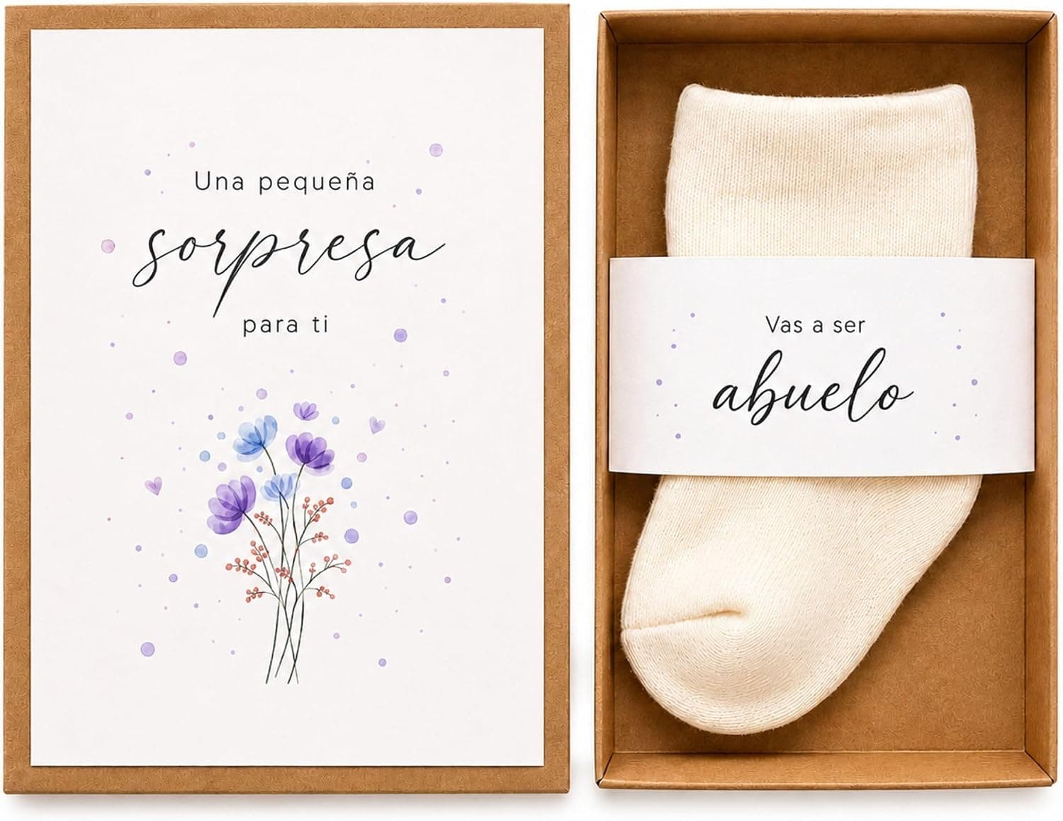Caja de papel kraft abierta con una tarjeta ilustrada con flores y un calcetín blanco de bebé con una faja que dice «vas a ser abuelo»