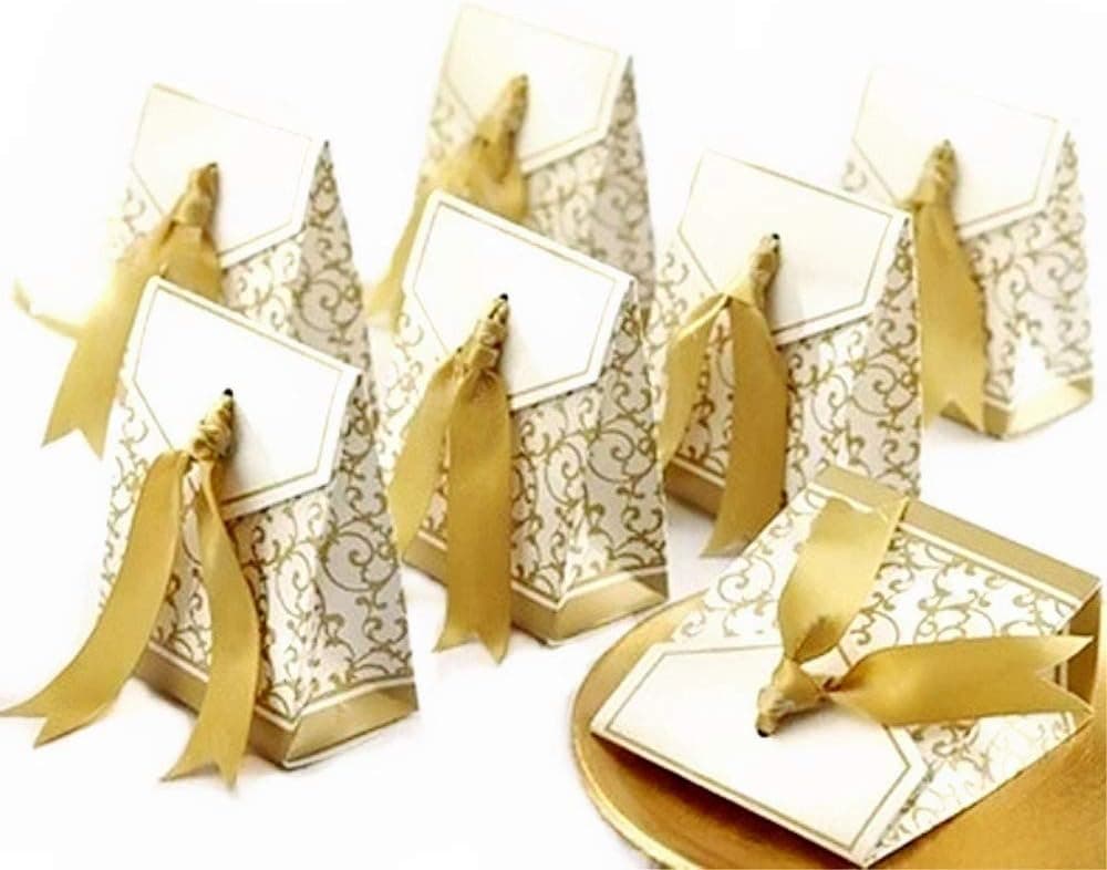 Varias cajitas de papel blanco con estampado dorado y lazo, colocadas sobre una mesa