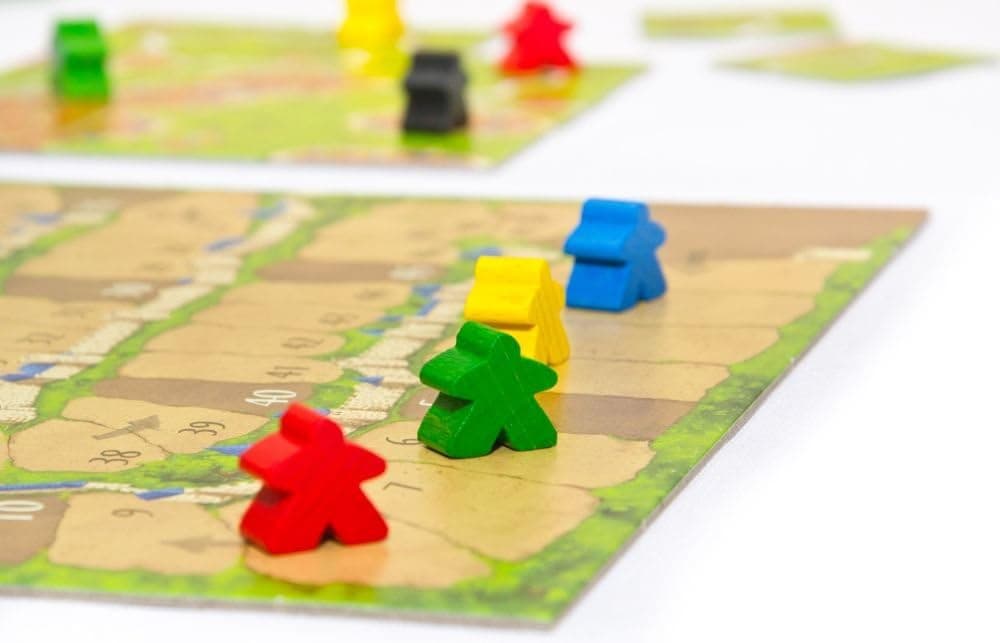 Detalle de las losetas colocadas sobre la mesa con los meeples de colores repartidos por caminos y campos
