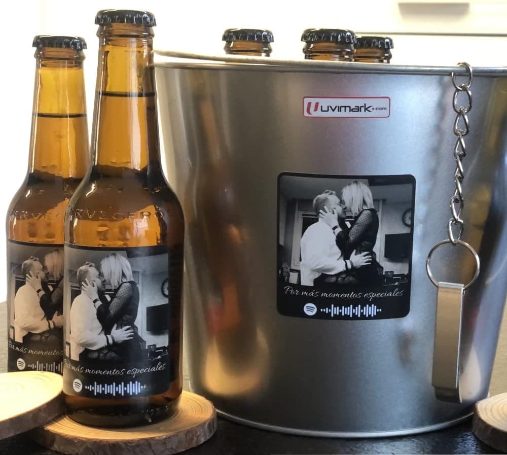 Cinco botellines con etiquetas de frases cerveceras distintas, alineados sobre la mesa