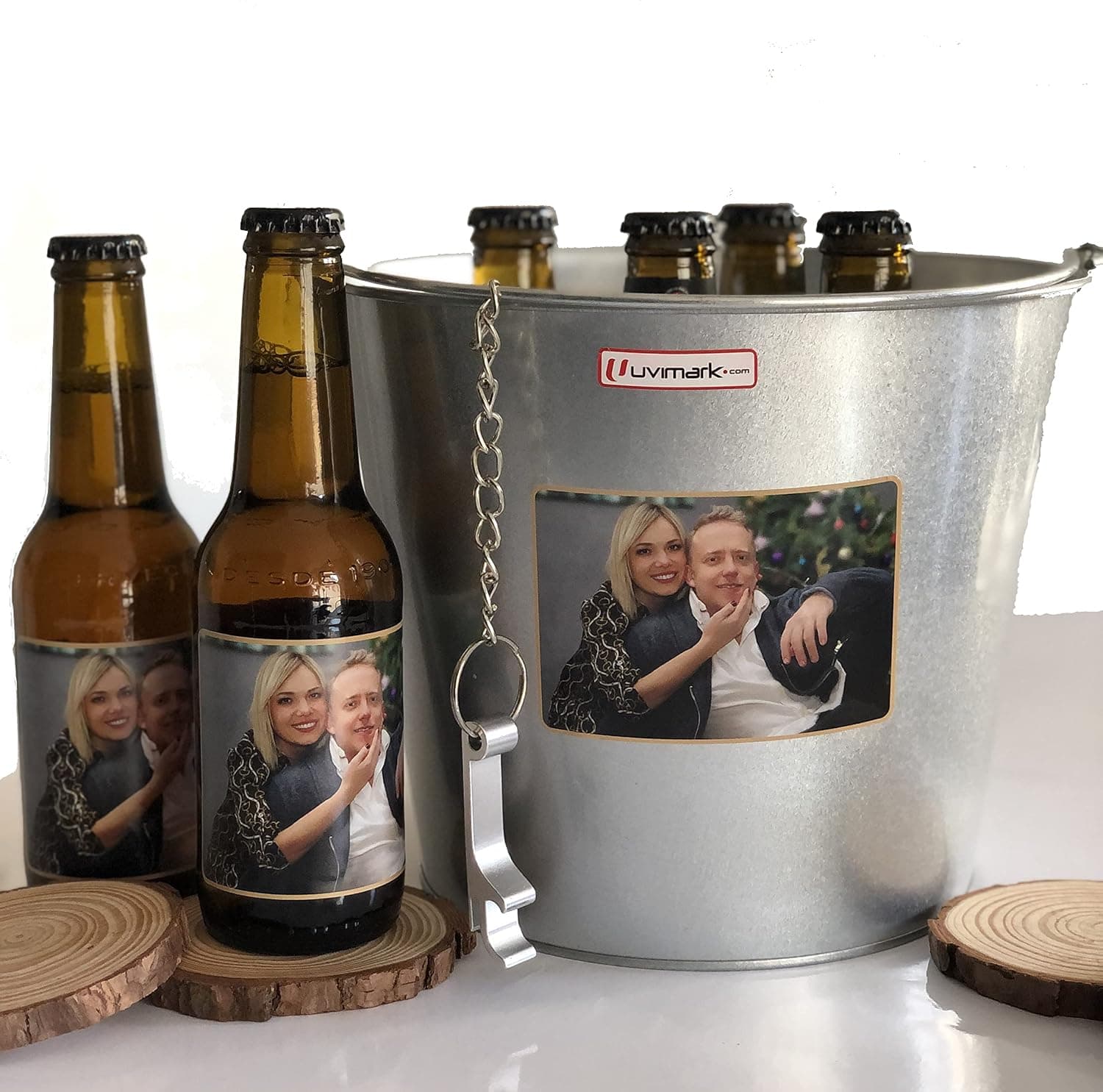Dos botellines con etiqueta personalizada apoyados en posavasos de madera, junto al cubo con su abrebotellas colgando