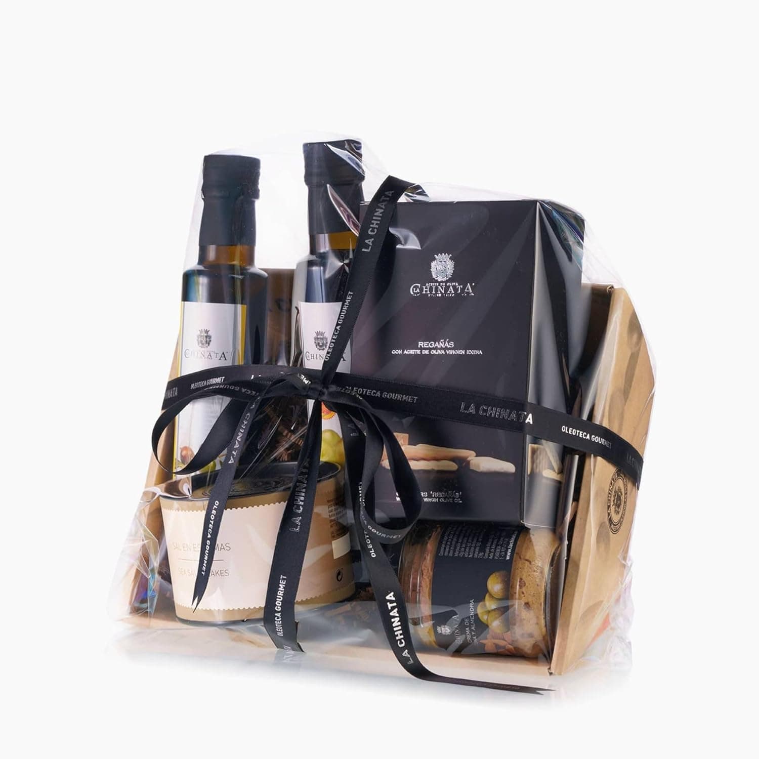 Cesta de mimbre de La Chinata con dos botellas de aceite y vinagre, sal en escamas, una caja de regañás y un tarro de crema untable, envuelta en celofán con lazo negro | /img/regalos/cesta-gourmet-la-chinata-pequena-2.jpg | Segunda imagen de la cesta gourmet pequeña La Chinata