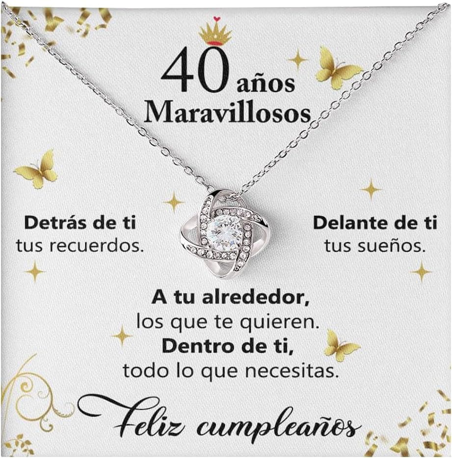 Collar con colgante en forma de nudo entrelazado y una circonita central, sobre una tarjeta con dedicatoria de cumpleaños con motivos de mariposas doradas