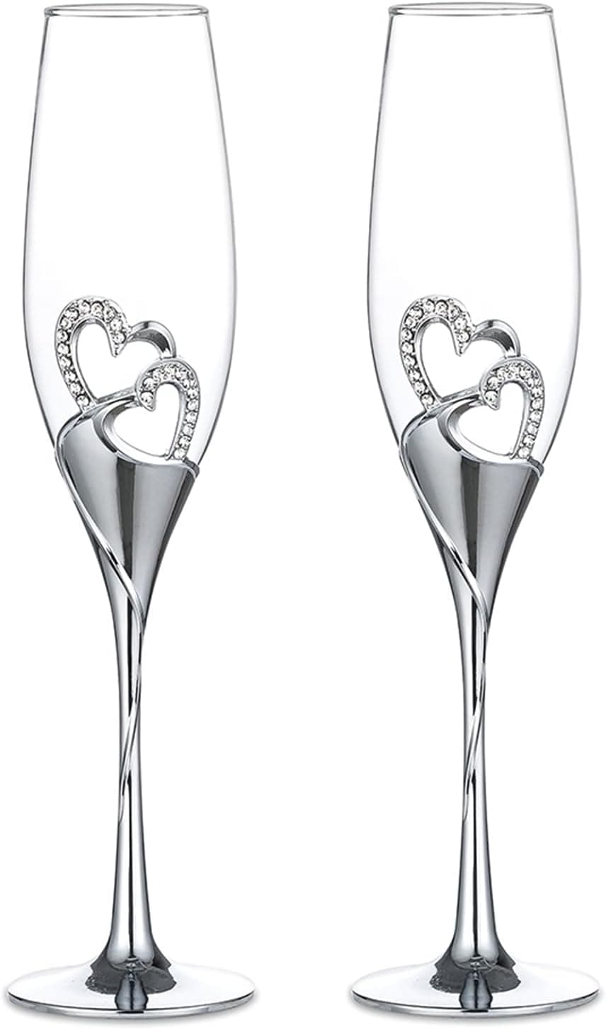 Par de copas de champán con dos corazones plateados unidos