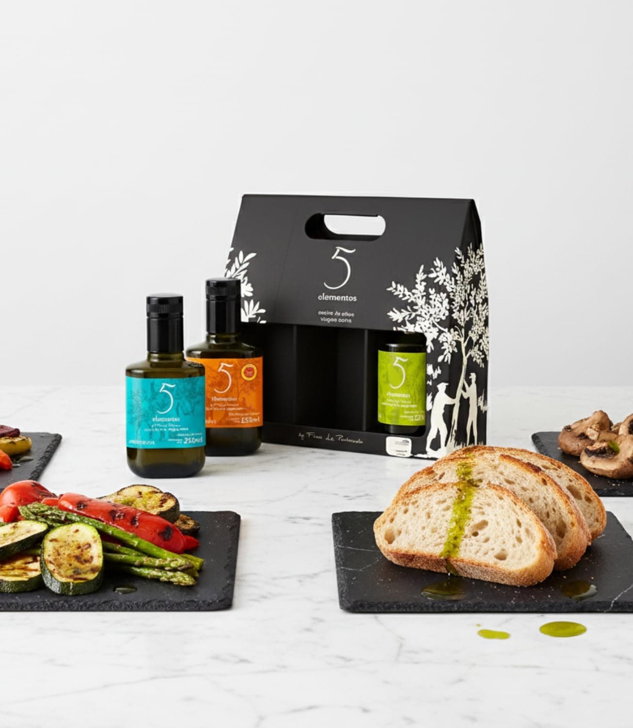 Las tres botellas junto a pan tostado con aceite y verduras a la plancha sobre pizarras