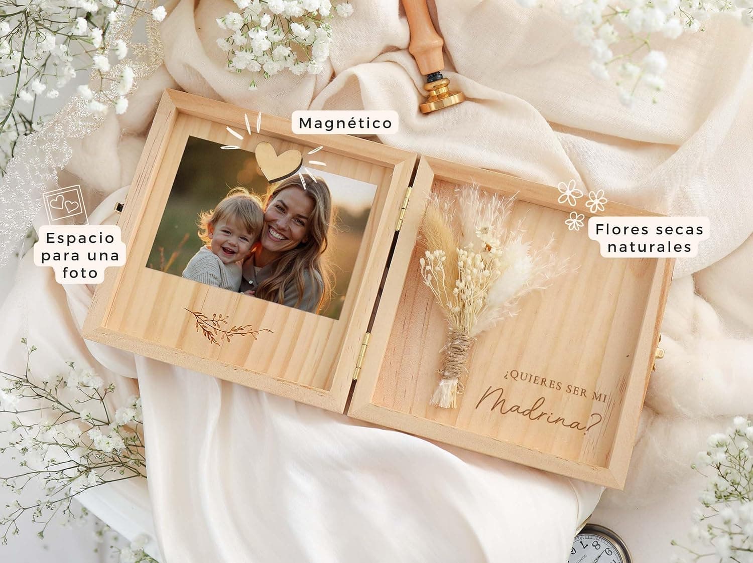 La caja abierta sobre una tela beige entre ramas de paniculata, con rótulos del fabricante que señalan «espacio para una foto», «magnético» y «flores secas naturales»