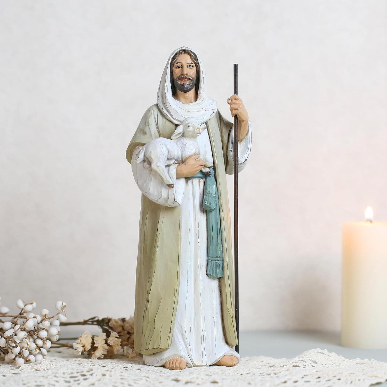 La misma figura sobre un tapete de ganchillo, con una vela encendida y unas flores secas al lado, para ver su tamaño en una mesa