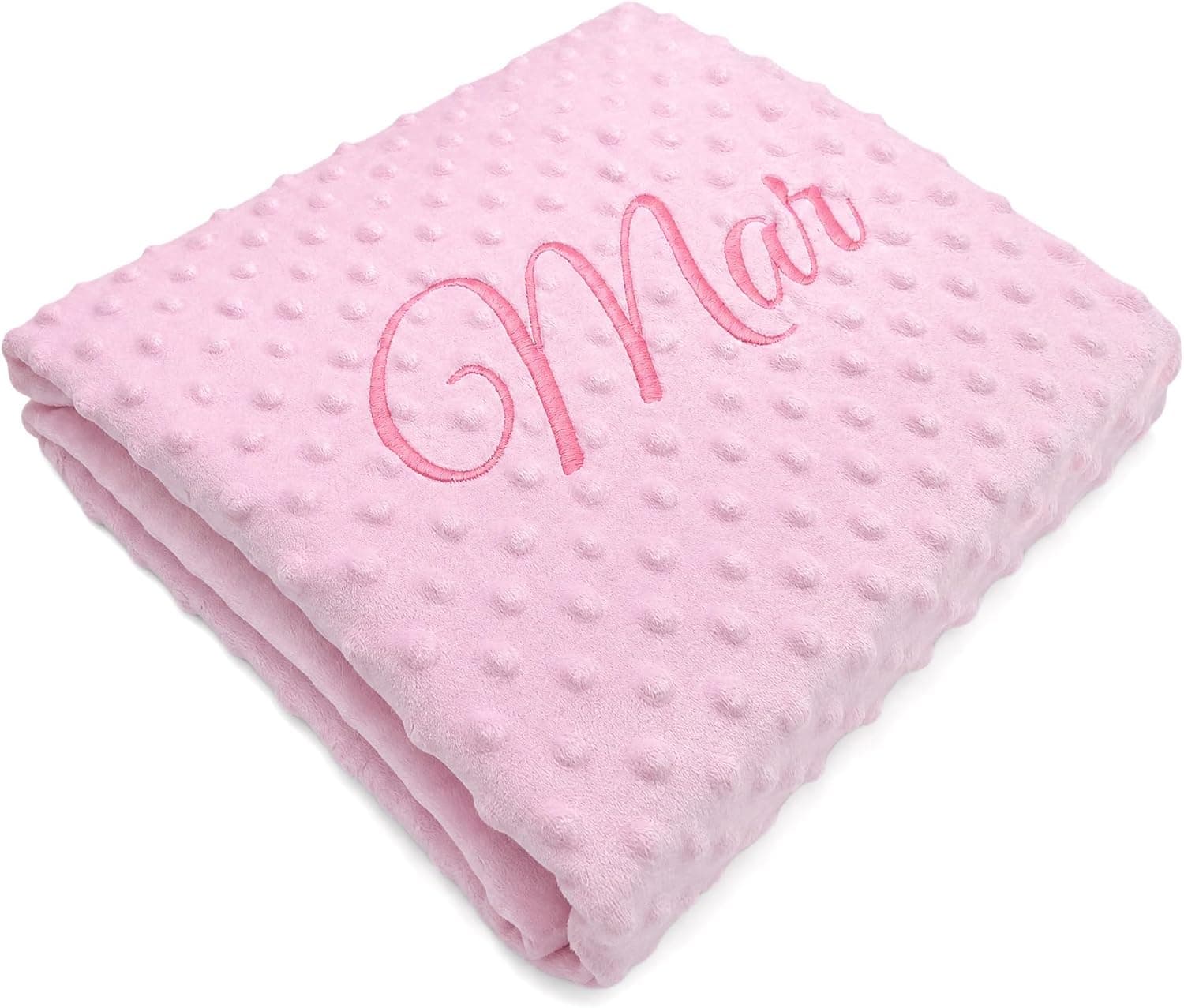 La manta rosa de tejido de topitos, doblada, con el nombre «Mar» bordado en hilo del mismo tono