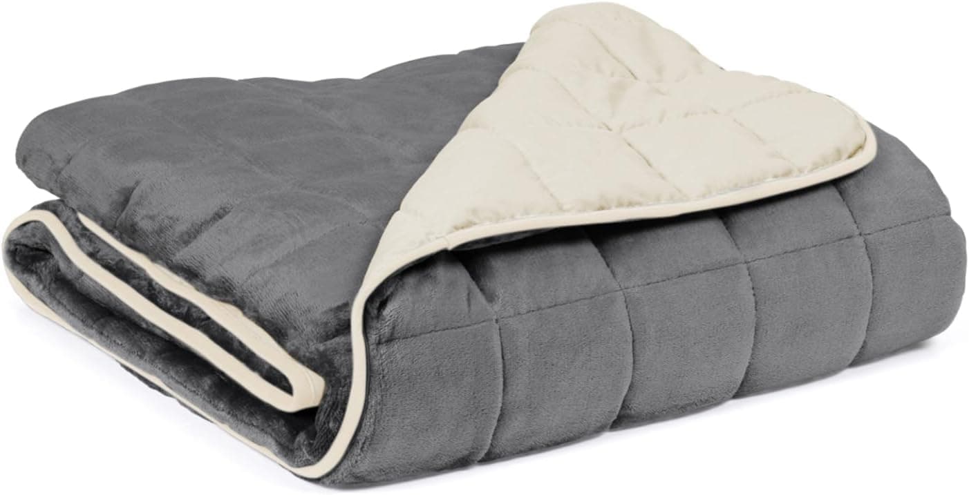 Manta pesada reversible bicolor gris y crema doblada sobre una cama