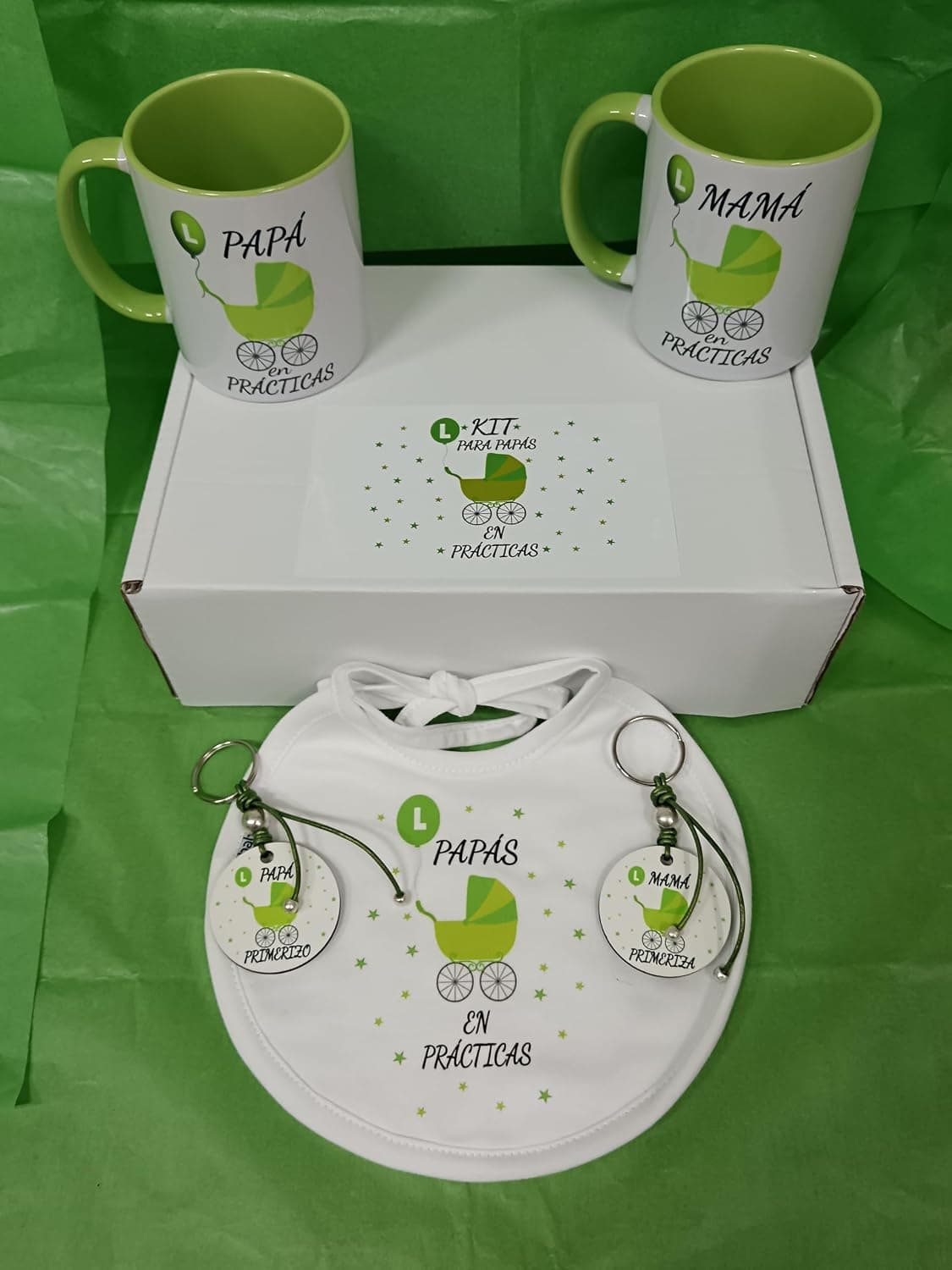 Caja de regalo con dos tazas de cerámica decoradas, dos llaveros de madera y un babero, todo con un cochecito a juego