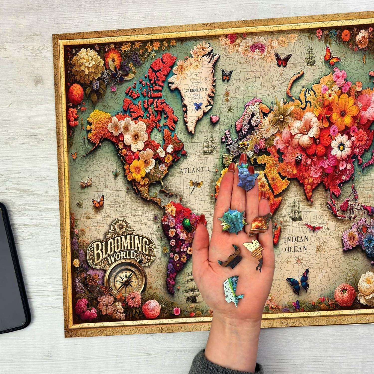 Mano sosteniendo piezas de madera con forma de animales sobre el mapa montado
