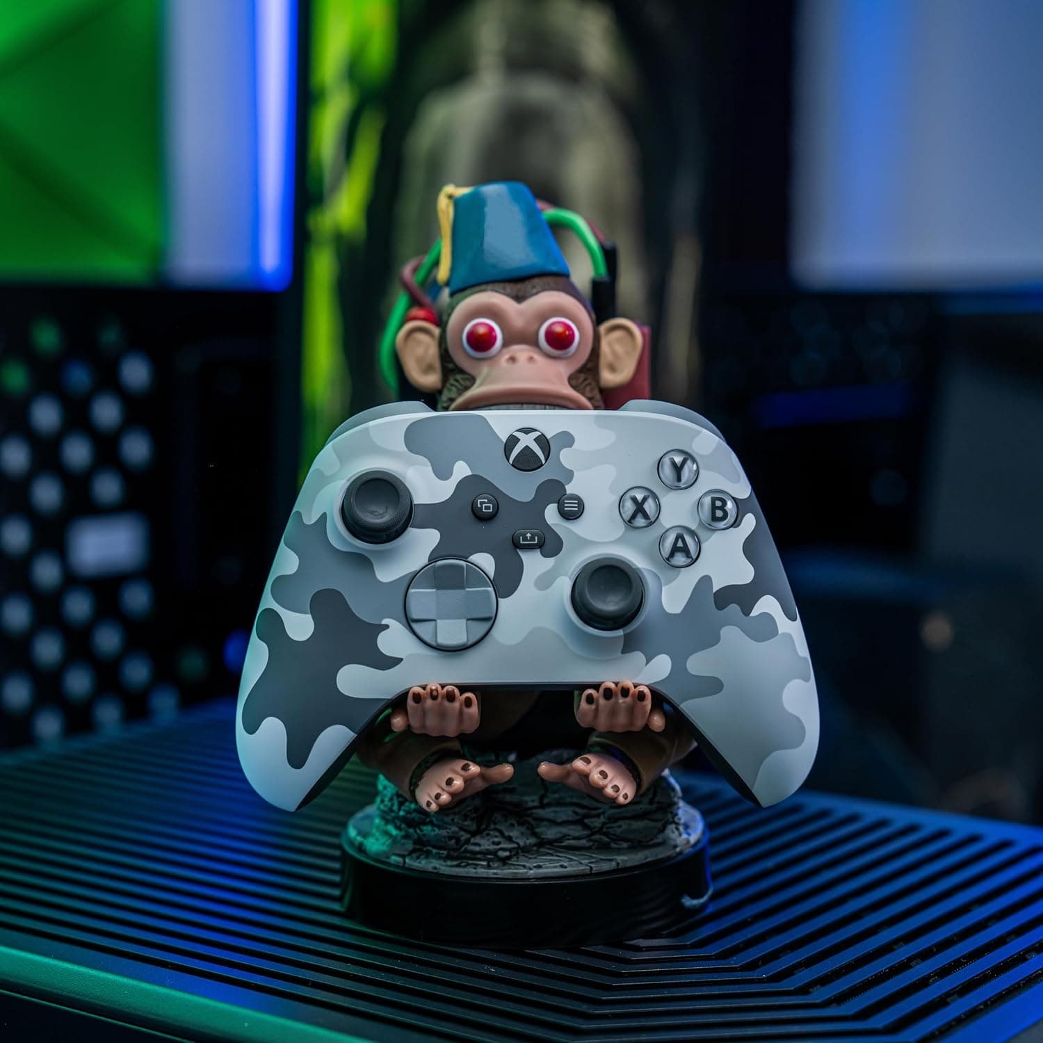 Figura soporte con forma de Monkey Bomb de Call of Duty, sujetando un mando y un móvil