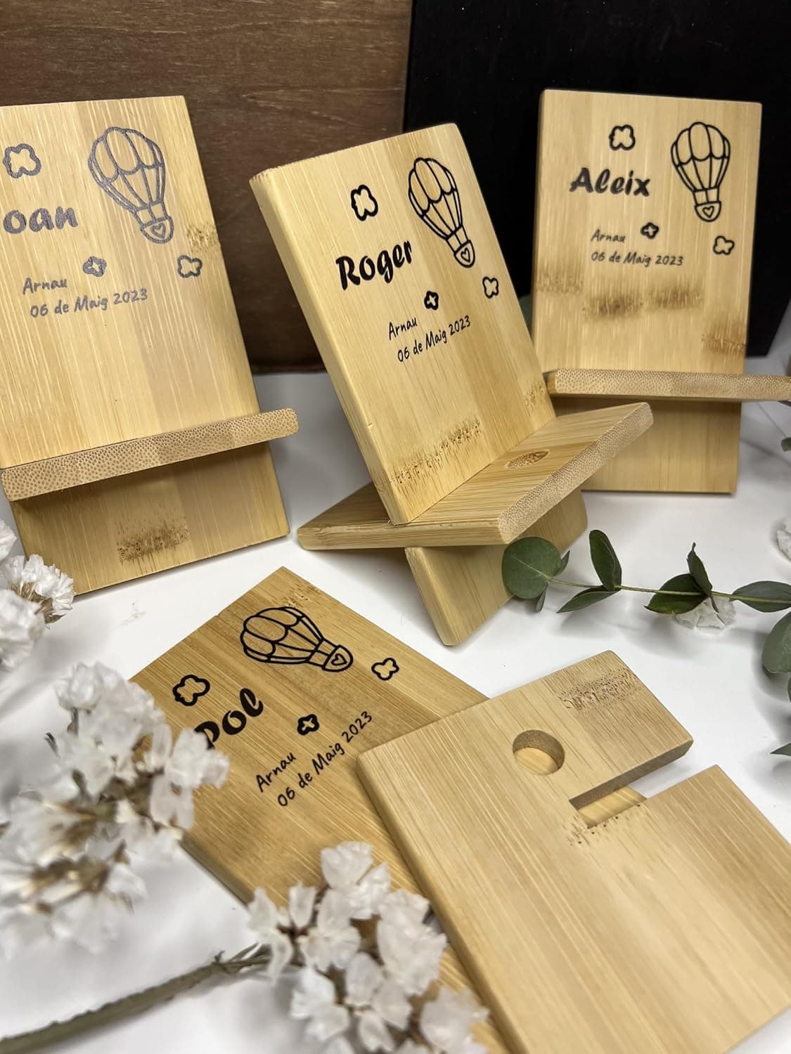 Varios soportes de madera para móvil grabados con distintos logotipos, mostrando otros usos del mismo producto