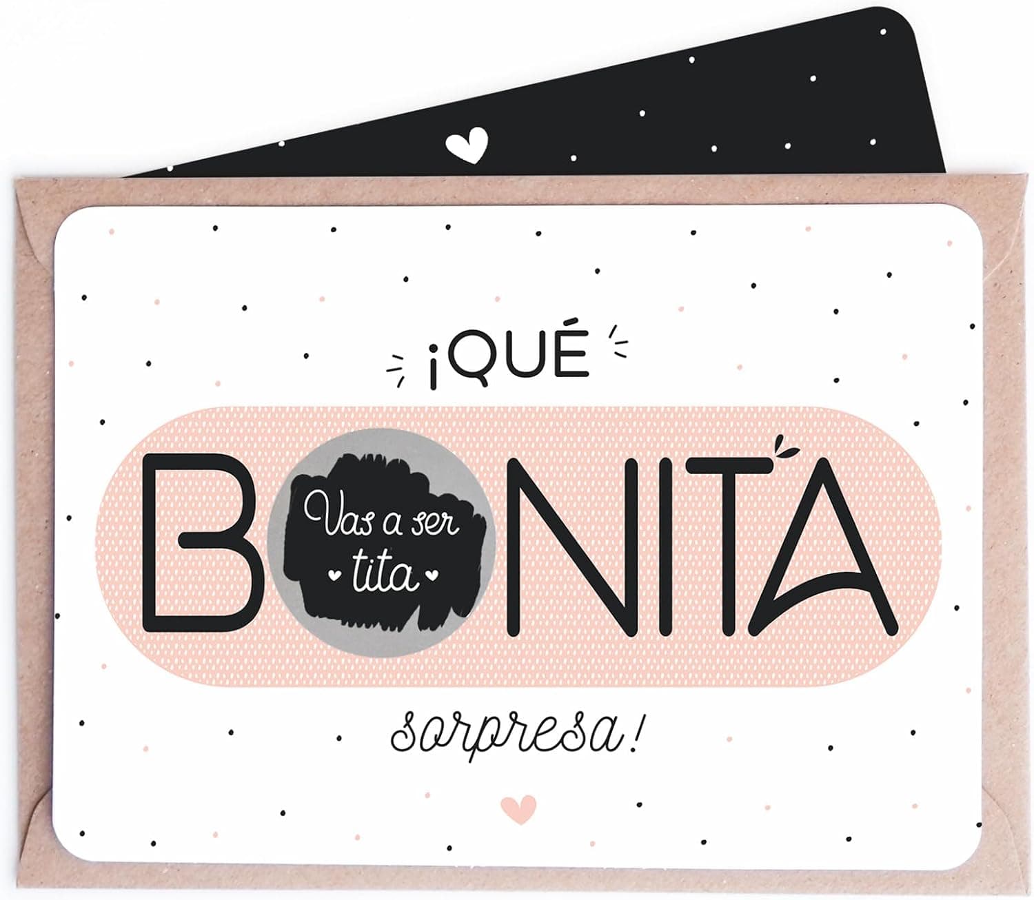 Tarjeta horizontal con «¡qué BONITA sorpresa!» donde la O es un círculo gris para rascar bajo el que se lee «vas a ser tita», con el sobre kraft detrás