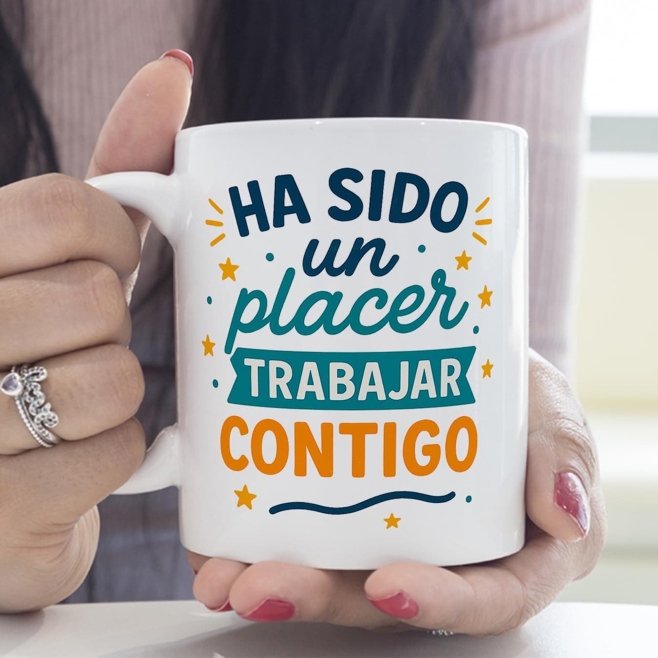 La taza sujeta por el asa con una mano, girada para ver que la frase también está impresa en la otra cara