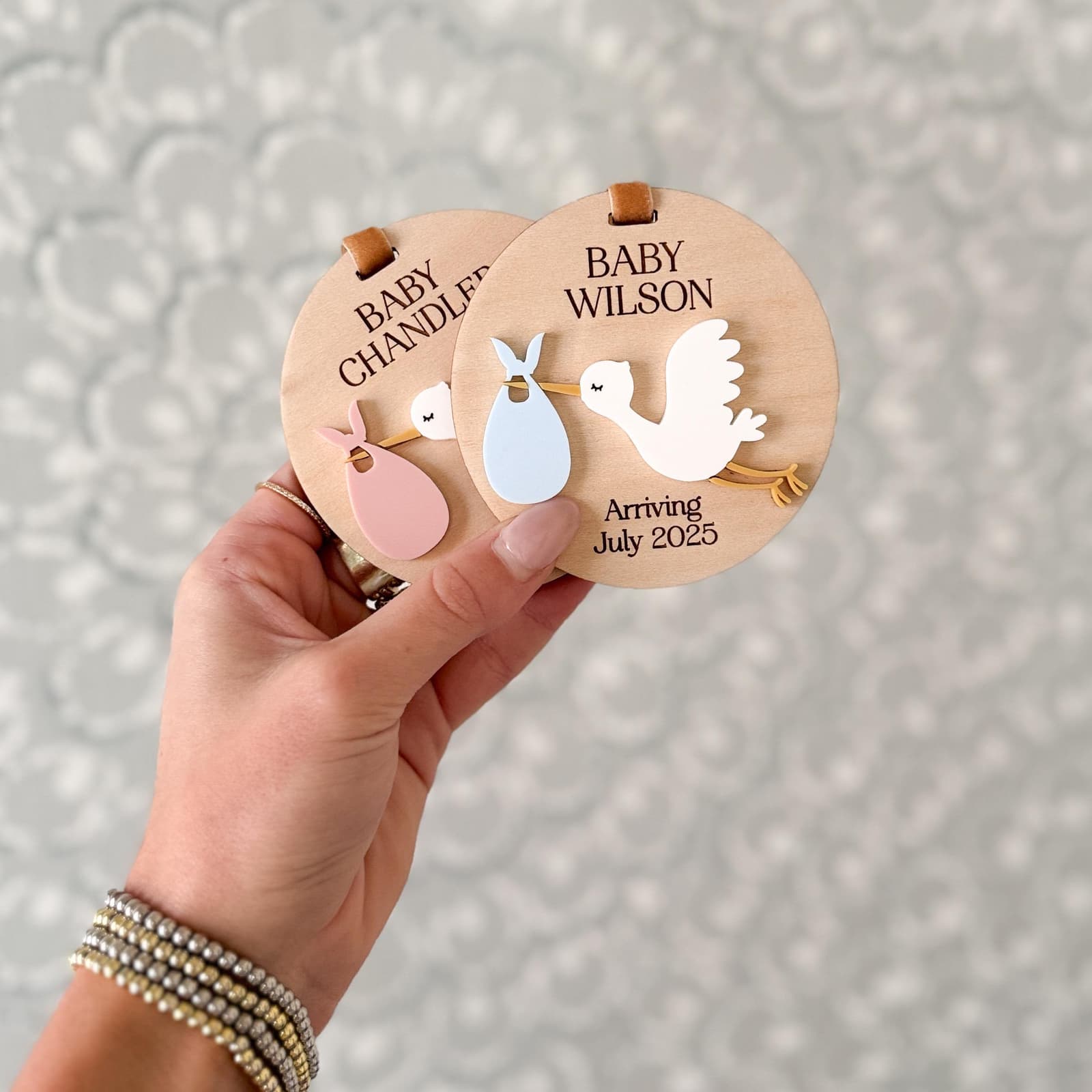 Layered wood and acrylic baby announcement ornament. Personalize with baby’s last name and arrival month and year. Features a white acrylic stork and customize with your choice of acrylic color for stork bag.