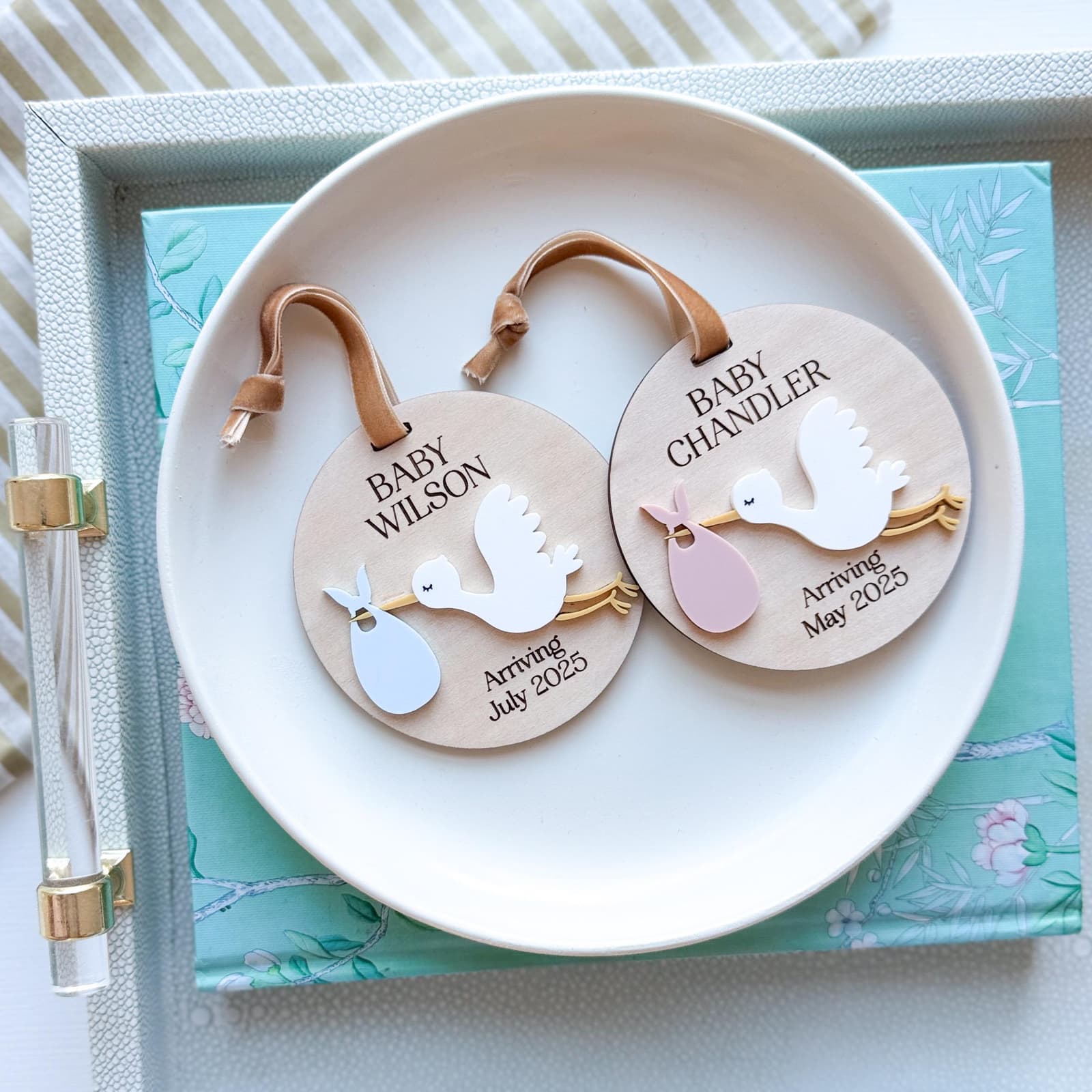 Layered wood and acrylic baby announcement ornament. Personalize with baby’s last name and arrival month and year. Features a white acrylic stork and customize with your choice of acrylic color for stork bag.