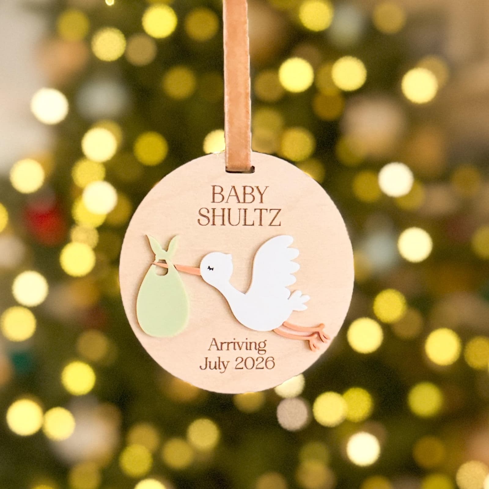 Layered wood and acrylic baby announcement ornament. Personalize with baby’s last name and arrival month and year. Features a white acrylic stork and customize with your choice of acrylic color for stork bag.