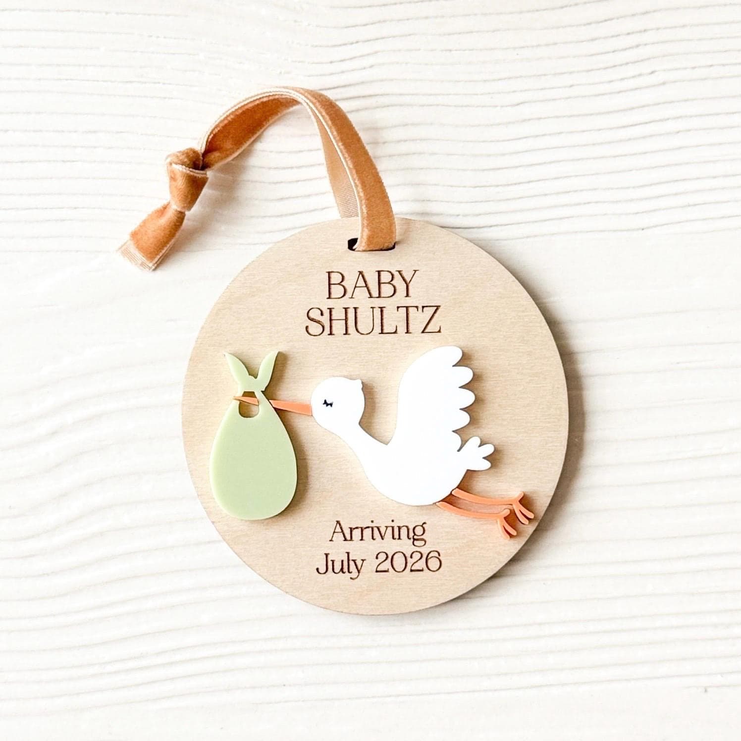 Layered wood and acrylic baby announcement ornament. Personalize with baby’s last name and arrival month and year. Features a white acrylic stork and customize with your choice of acrylic color for stork bag.
