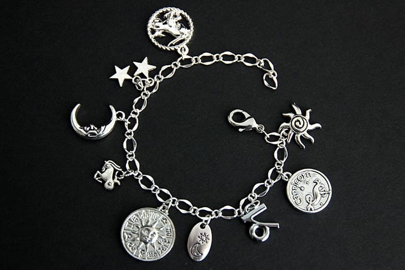 Pulsera de plata con siete amuletos de Capricornio, incluida la luna, el sol y una moneda con el símbolo del signo