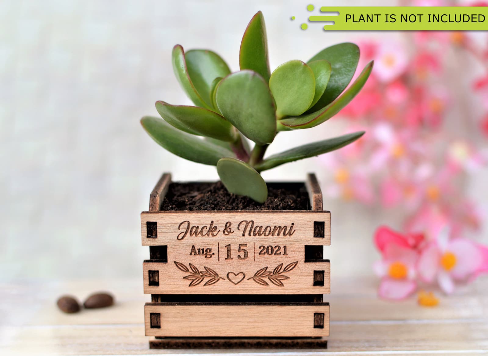 Mini cajón de madera con listones, grabado con los nombres de los novios y la fecha de la boda, con una suculenta pequeña plantada dentro