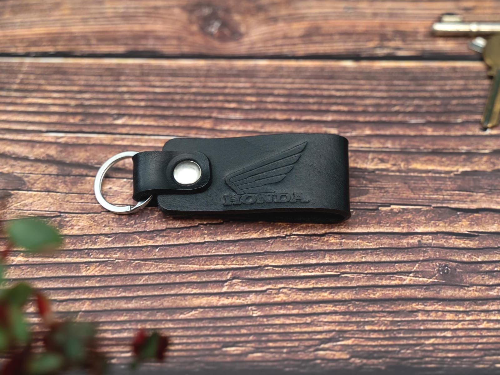Folded black keyring/keychain embossed with the Honda motorbike logo. Stainless steel split ring and rivet.