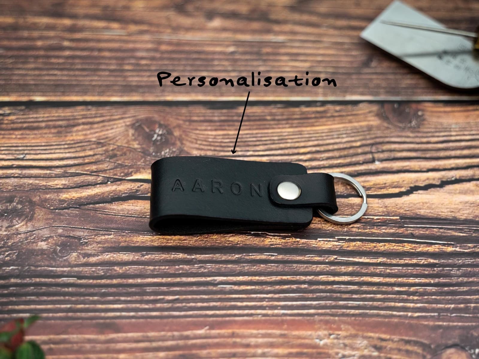 Folded black keyring embossed with name showing personalisation. Stainless steel split ring and rivet.