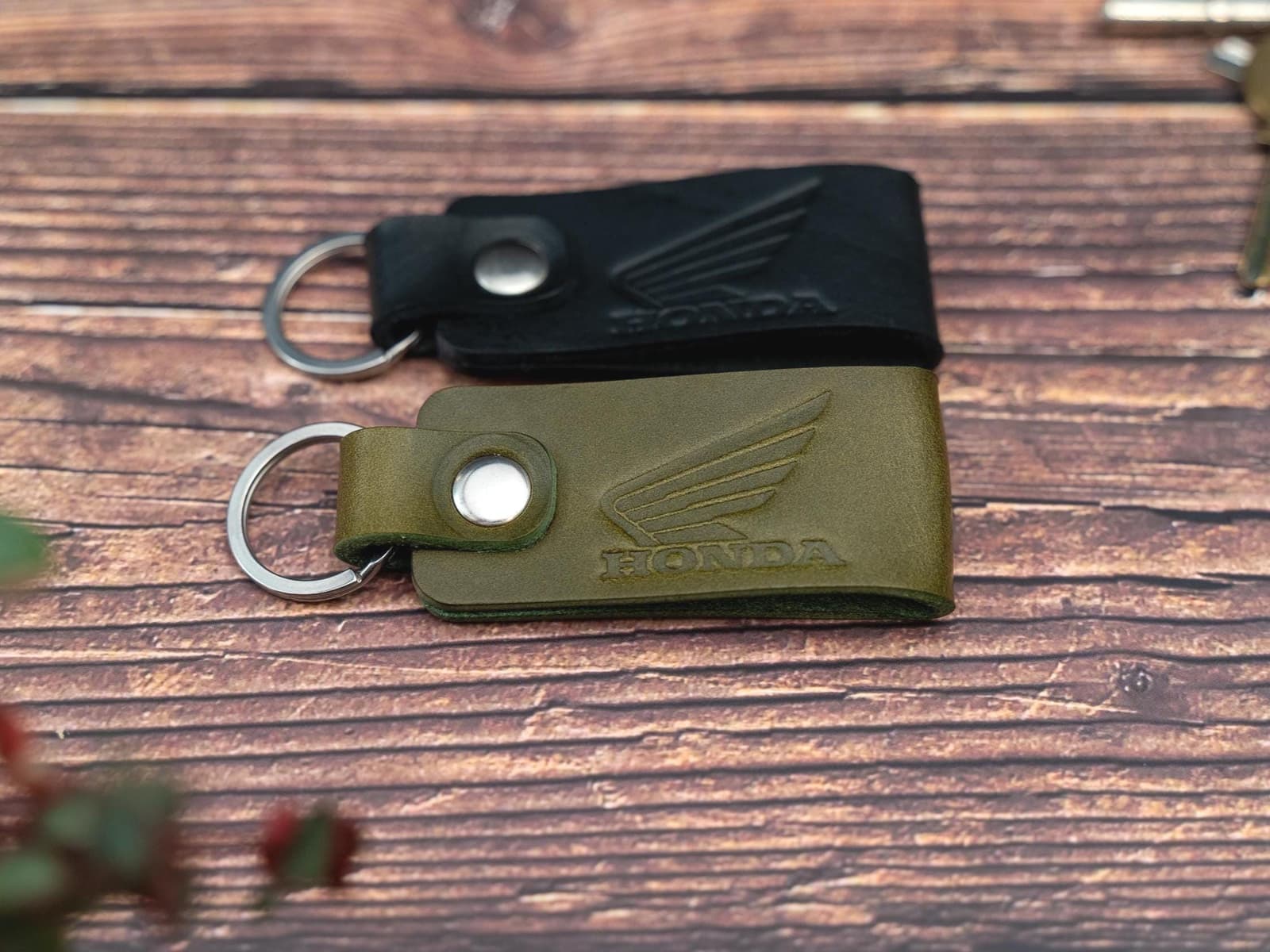 Folded black and olive green keyrings/keychains embossed with the Honda motorbike logo. Stainless steel split ring and rivet.