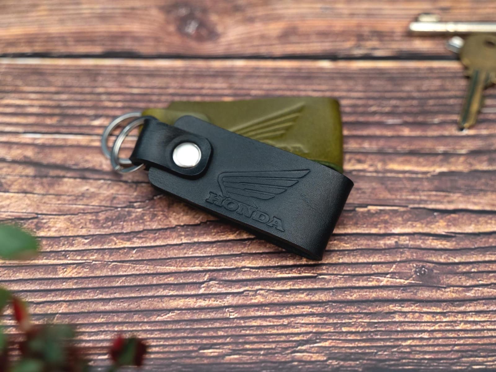Folded black and olive green keyrings/keychains embossed with the Honda motorbike logo. Stainless steel split ring and rivet.