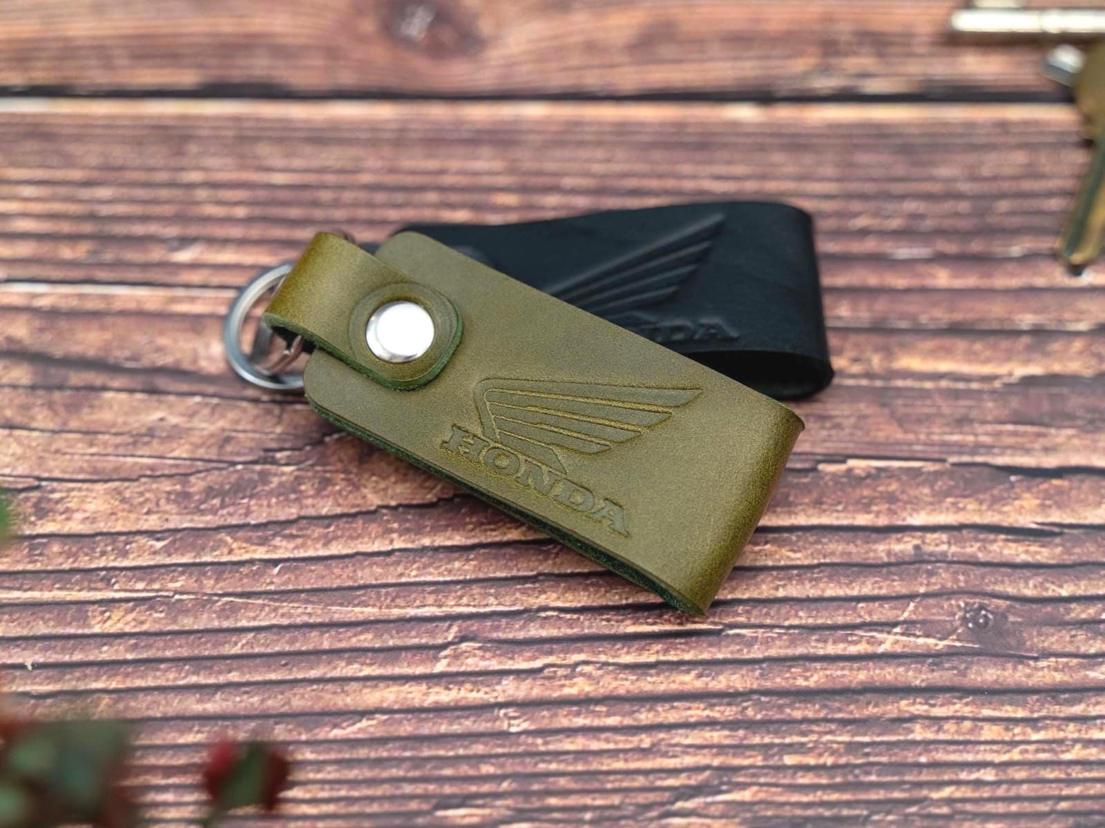 Folded black and olive green keyrings/keychains embossed with the Honda motorbike logo. Stainless steel split ring and rivet.