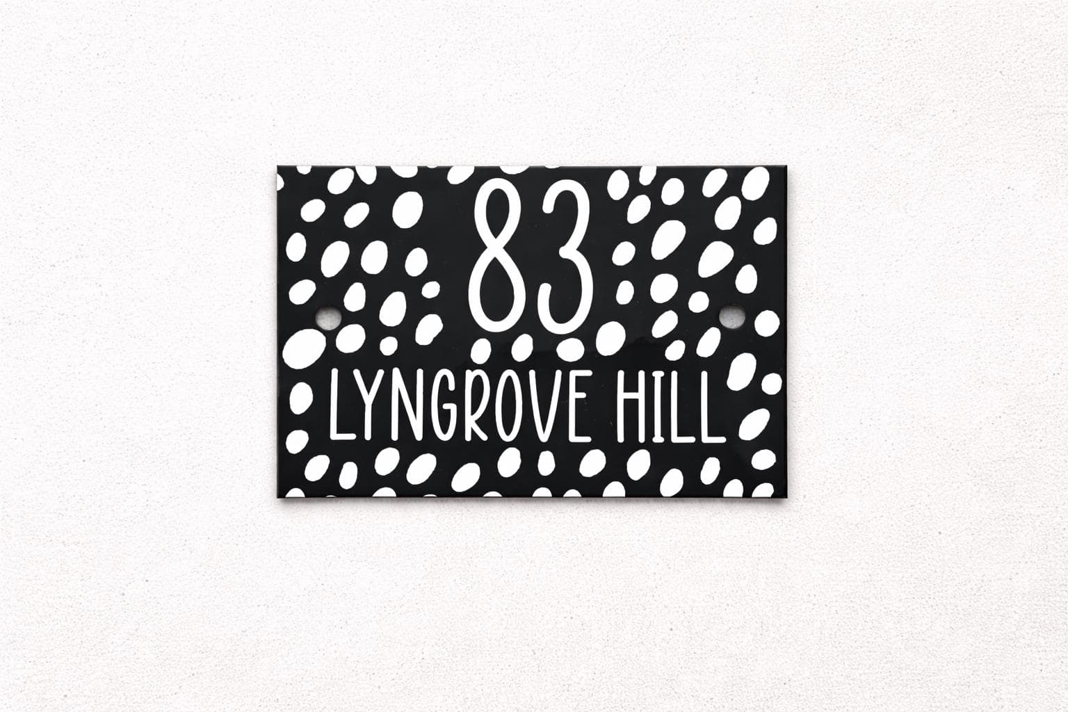 Personalised house sign with white lettering on a black patterned background
