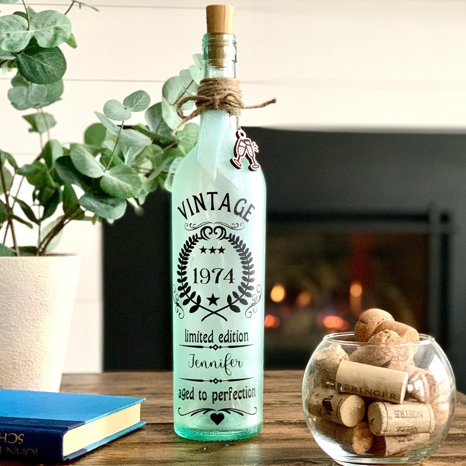 Recycled Clear Wine Bottle sprayed with frosted paint. Black Vinyl words: Vintage limited edition aged to perfection with first name and birthday date. Includes battery operated fairy lights attached to plastic wine cork with on/off switch. Choice of Twine and ribbons.,