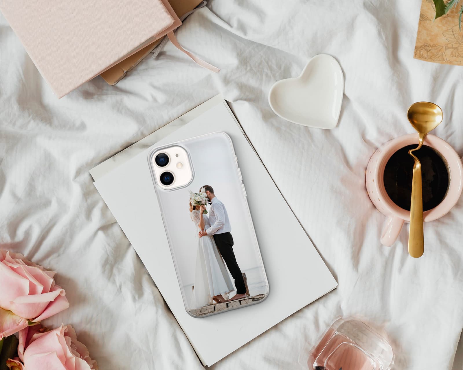 Funda de móvil con la foto de una pareja, junto a una libreta y una taza con forma de corazón