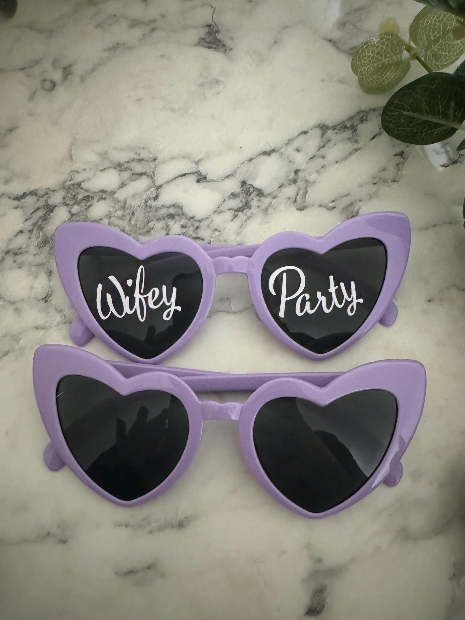 Gafas de sol de corazón rosa puestas, mostrando el nombre grabado en la patilla