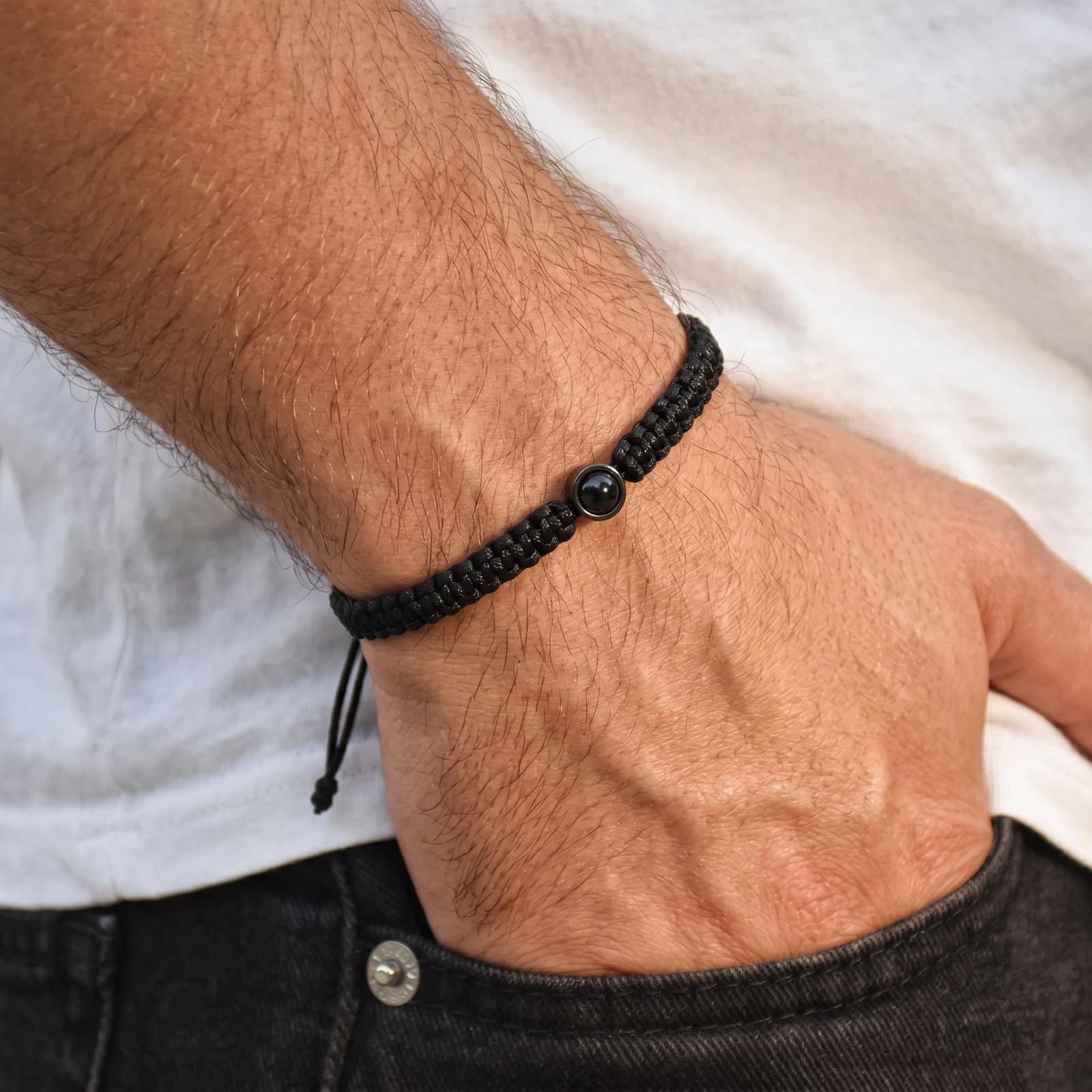 Pulsera de cuero trenzado negro con un colgante circular de plata que muestra una foto proyectada
