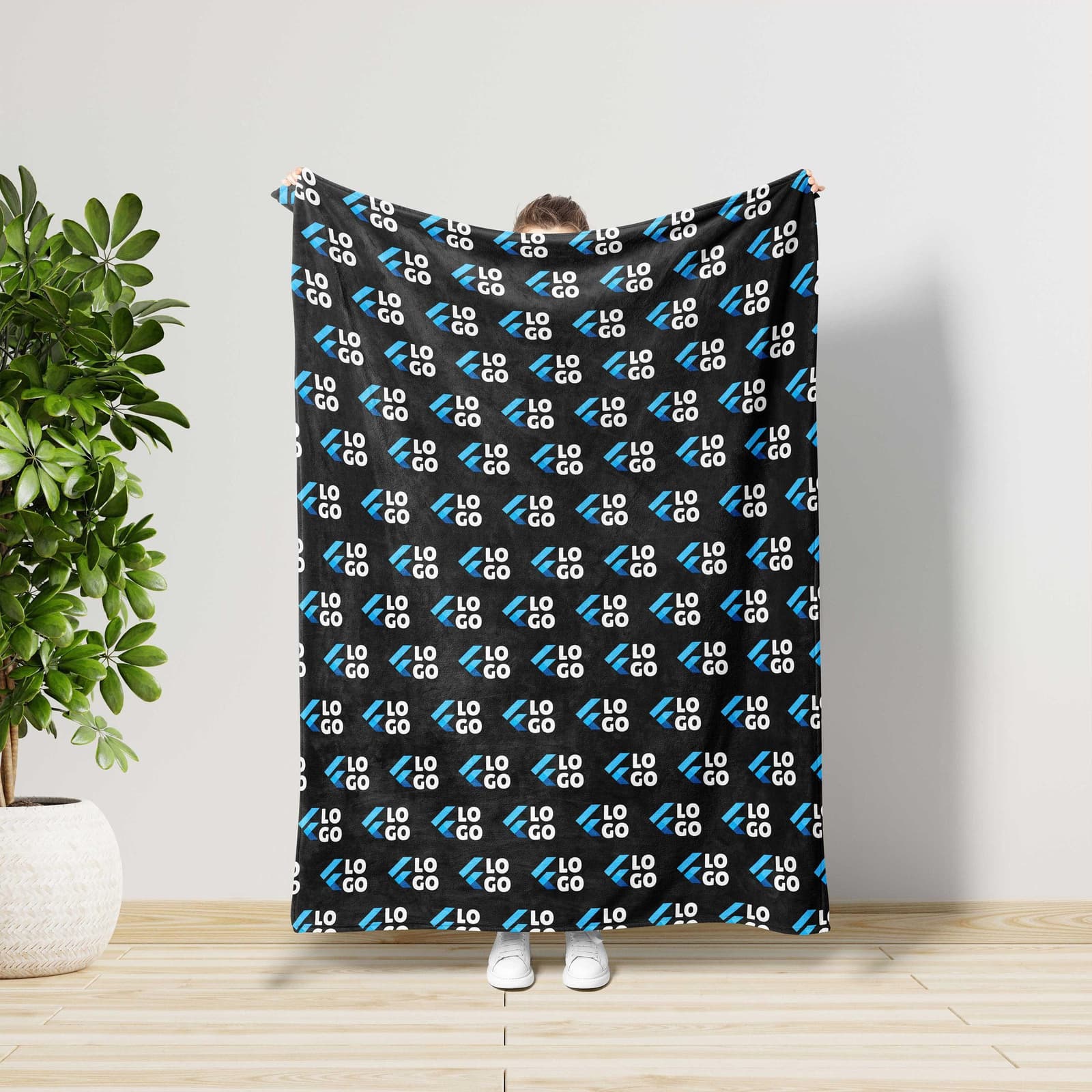 A person is holding up a black and blue blanket with the repeated logo "LO" on it.