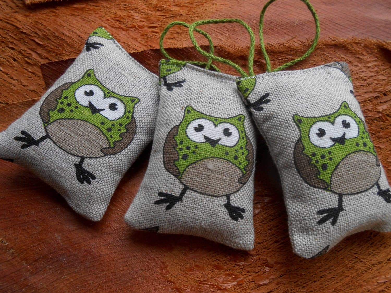 Tres saquitos de tela de arpillera con forma de búho, rellenos de lavanda seca, con un cordón para colgar