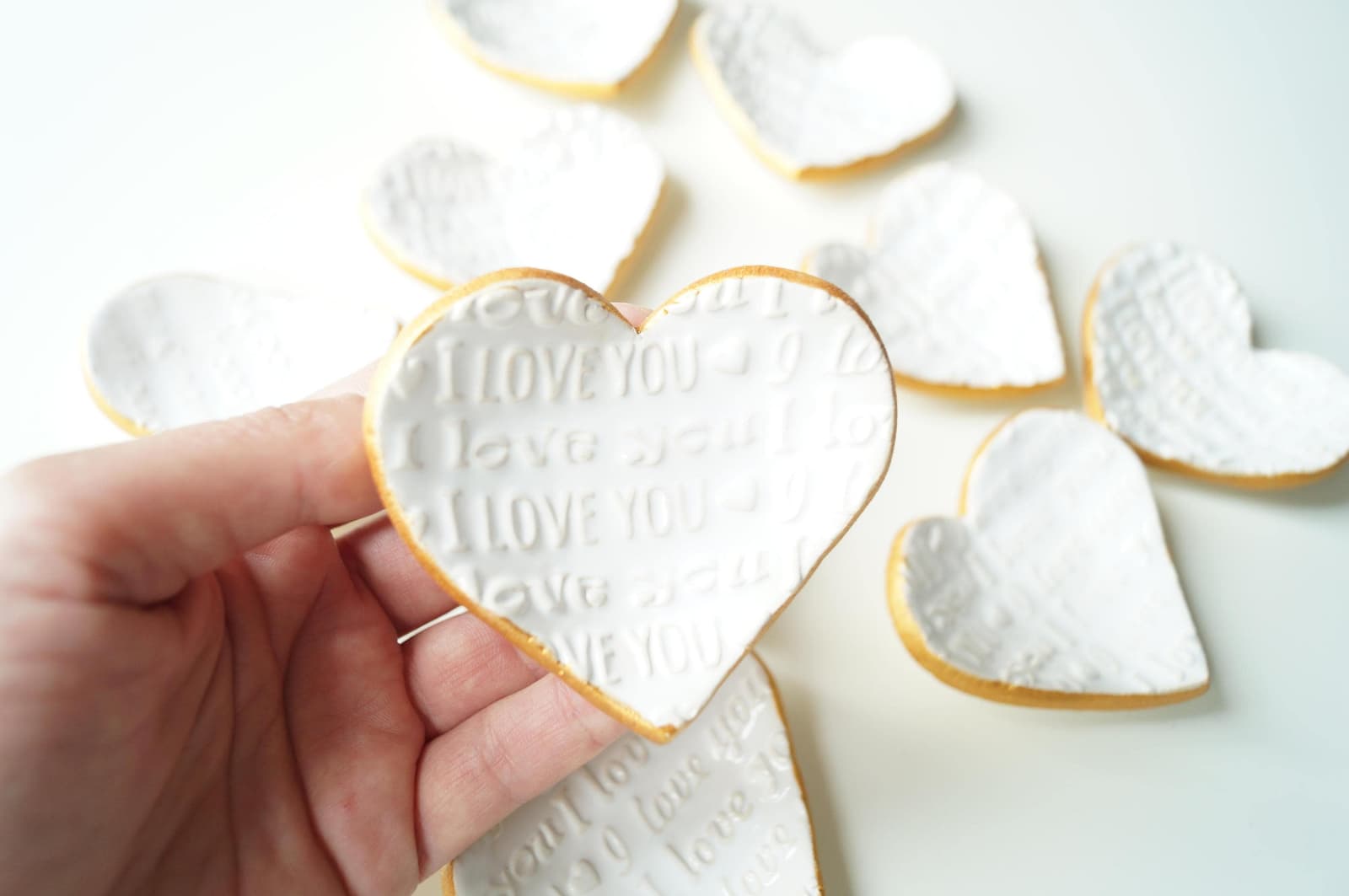 Platitos de cerámica blanca con forma de corazón y borde dorado, con texto grabado en relieve