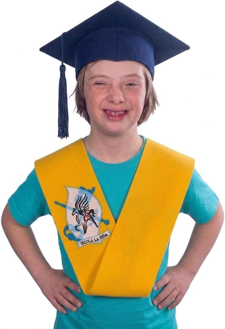 Niño con birrete de graduación azul y banda amarilla con escudo bordado