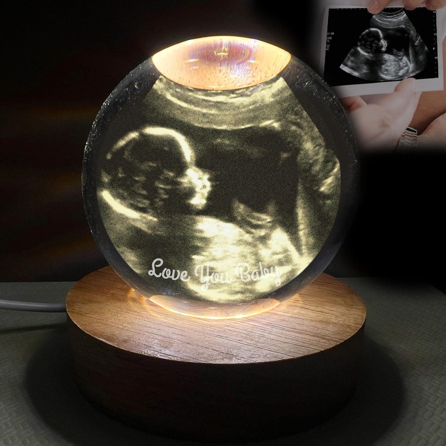 Bola de cristal iluminada desde abajo por una base de madera, con la ecografía grabada en el interior y un texto en la parte baja