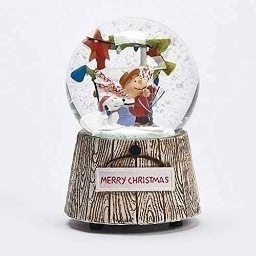 Globo musical de nieve con Charlie Brown y Snoopy decorando, con el texto We Wish You A Merry Christmas
