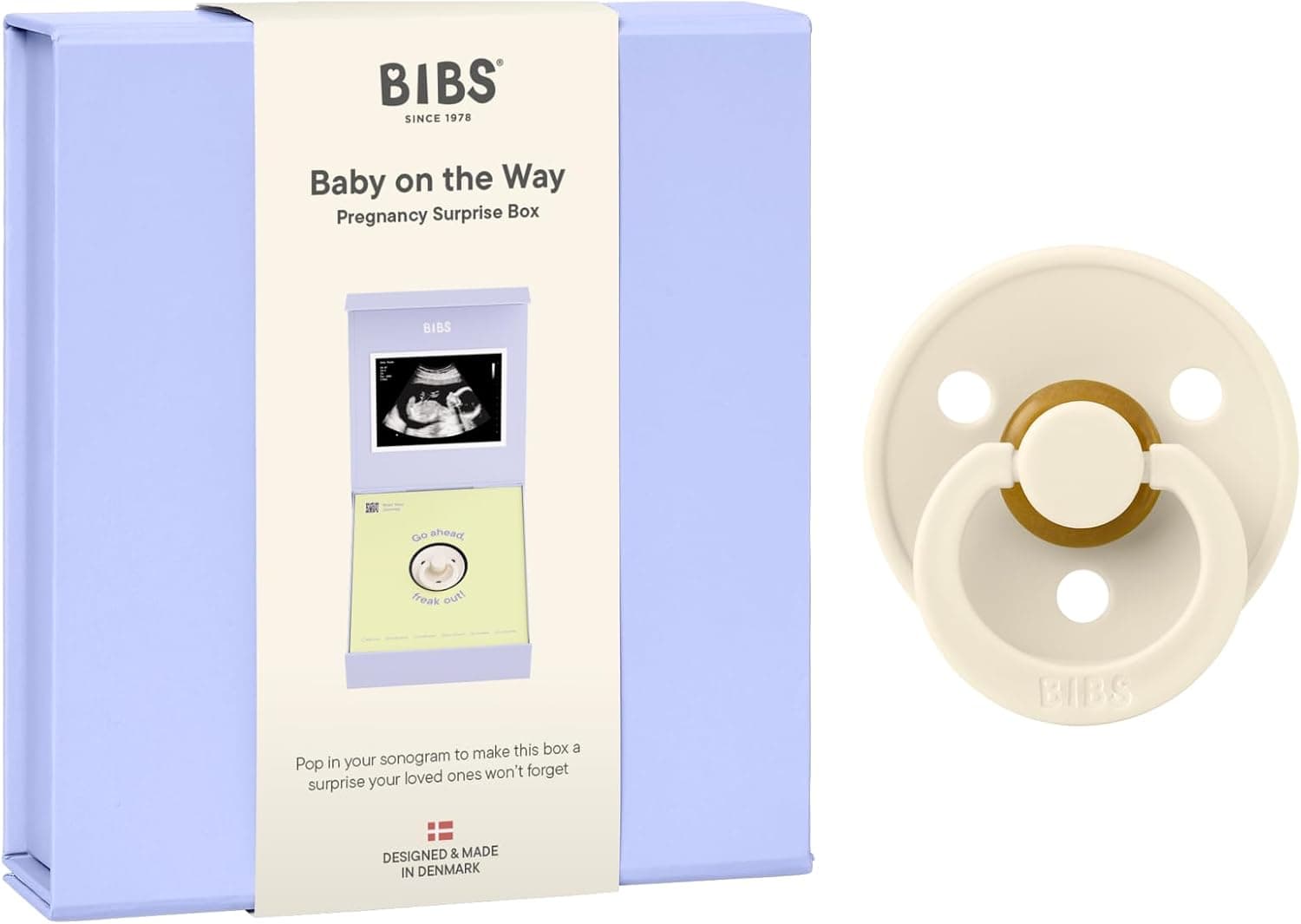 Caja azul lavanda con faja de papel crema donde se lee «BIBS Baby on the Way, Pregnancy Surprise Box», y al lado el chupete Colour en color crema con la tetina de látex