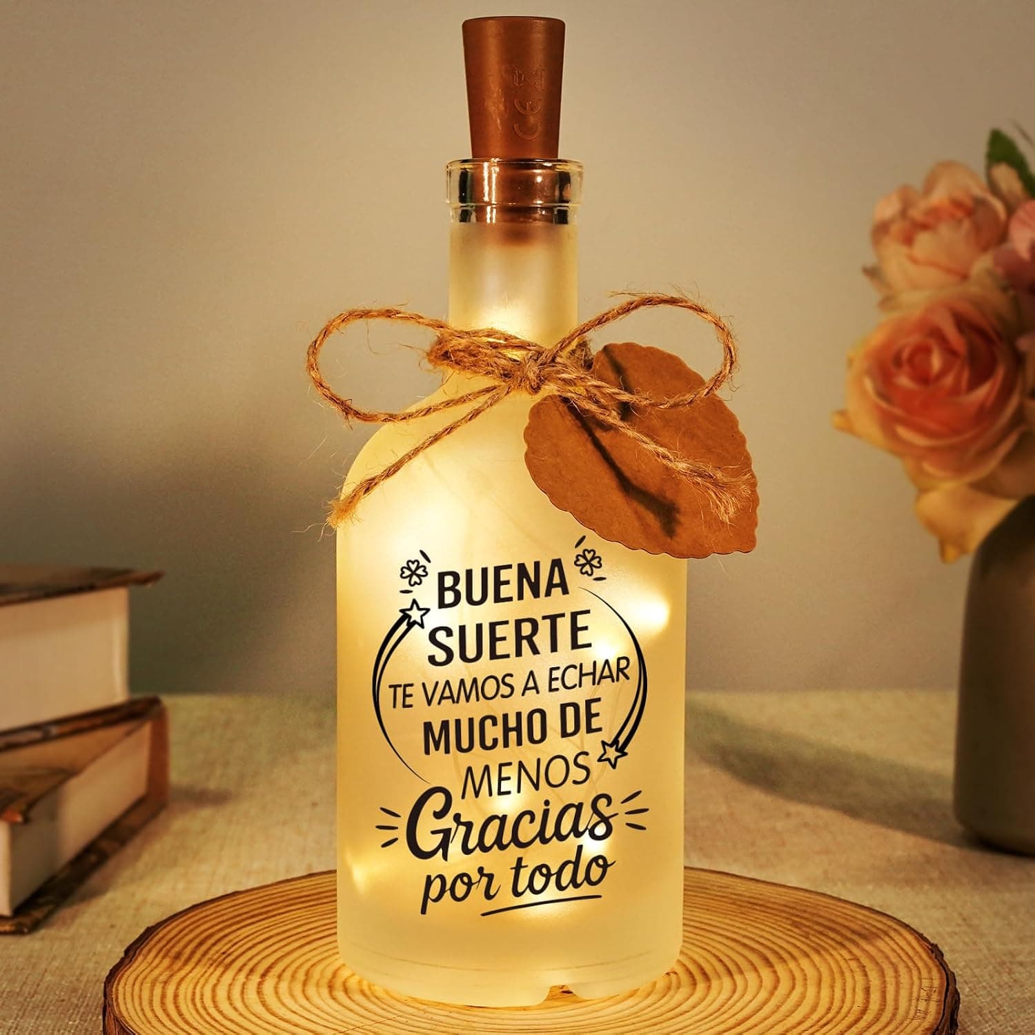 Botella de vidrio esmerilado encendida por dentro con luz cálida, con la frase de agradecimiento impresa y un cordel de yute al cuello
