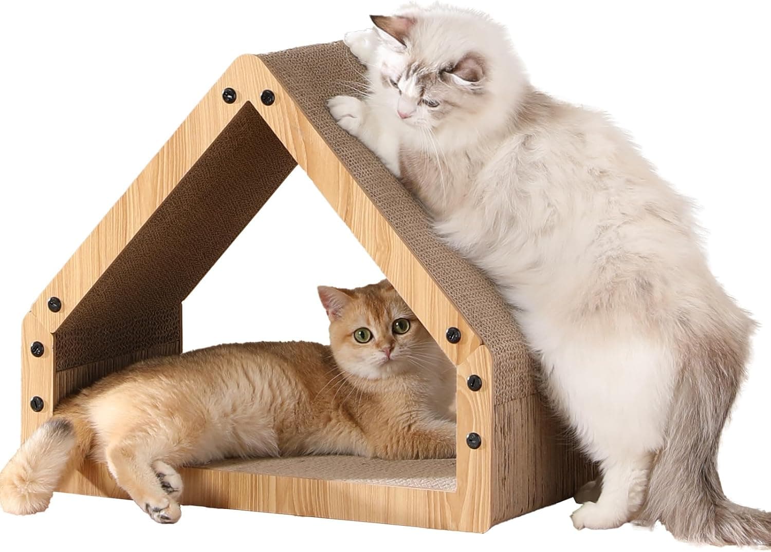 La casita de cartón con el tejado a dos aguas y los laterales de madera clara, con dos gatos, uno encima del tejado y otro tumbado dentro