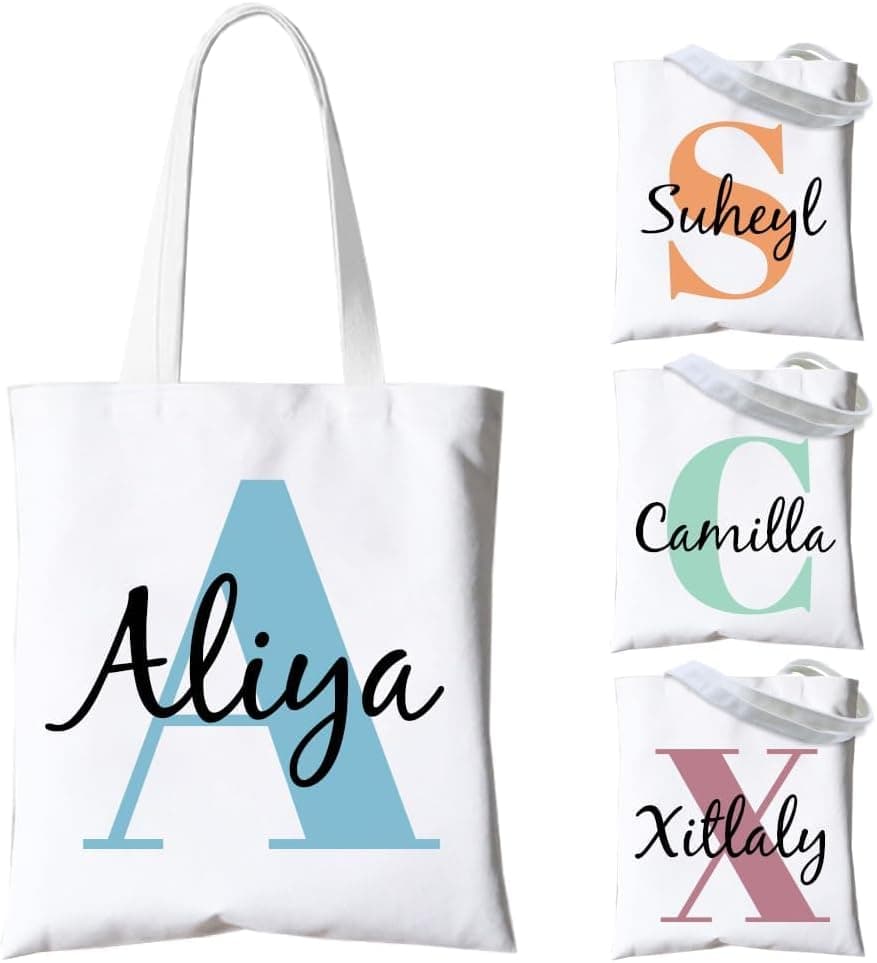 Bolso tote blanco con la inicial "A" en azul y el nombre "Aliya", junto a otras variantes con distintos nombres e iniciales en distintos colores