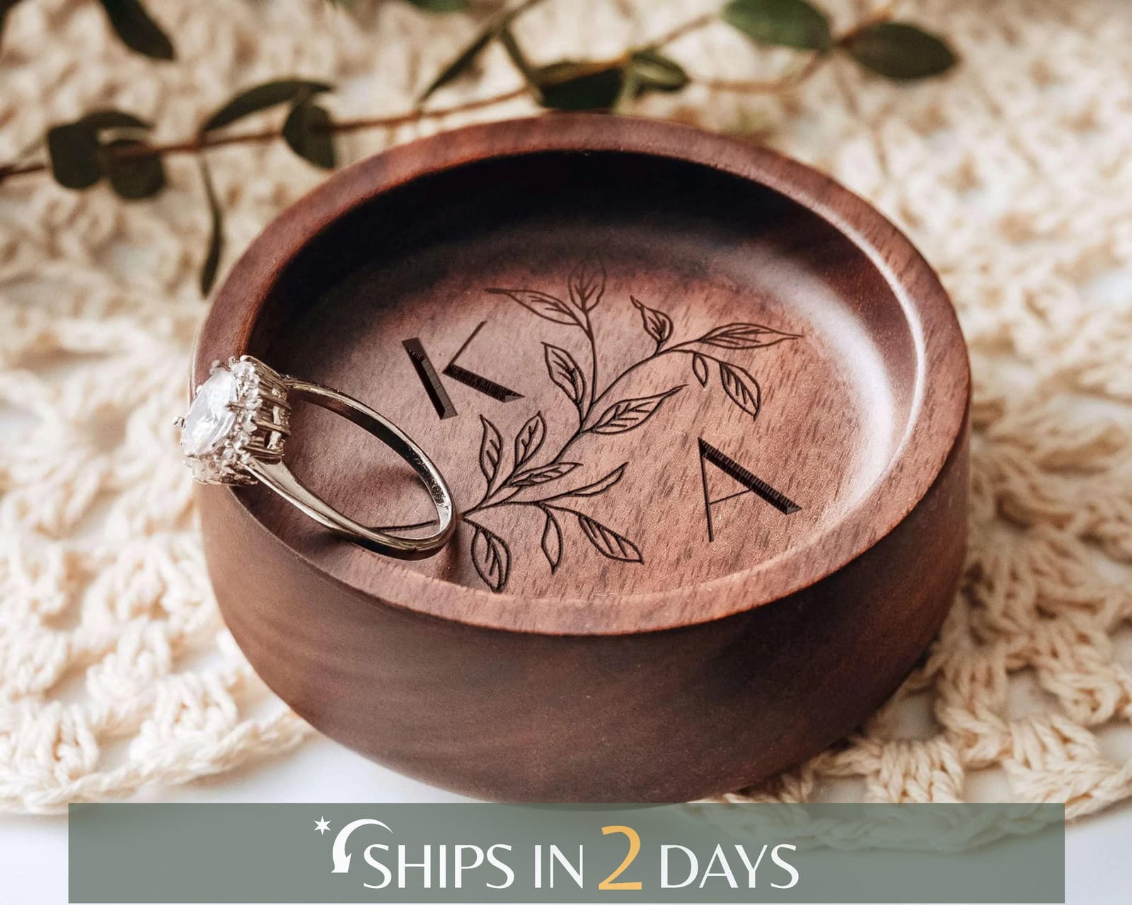 A wooden ring holder with a ring placed inside it, and the holder has a leaf design on it.